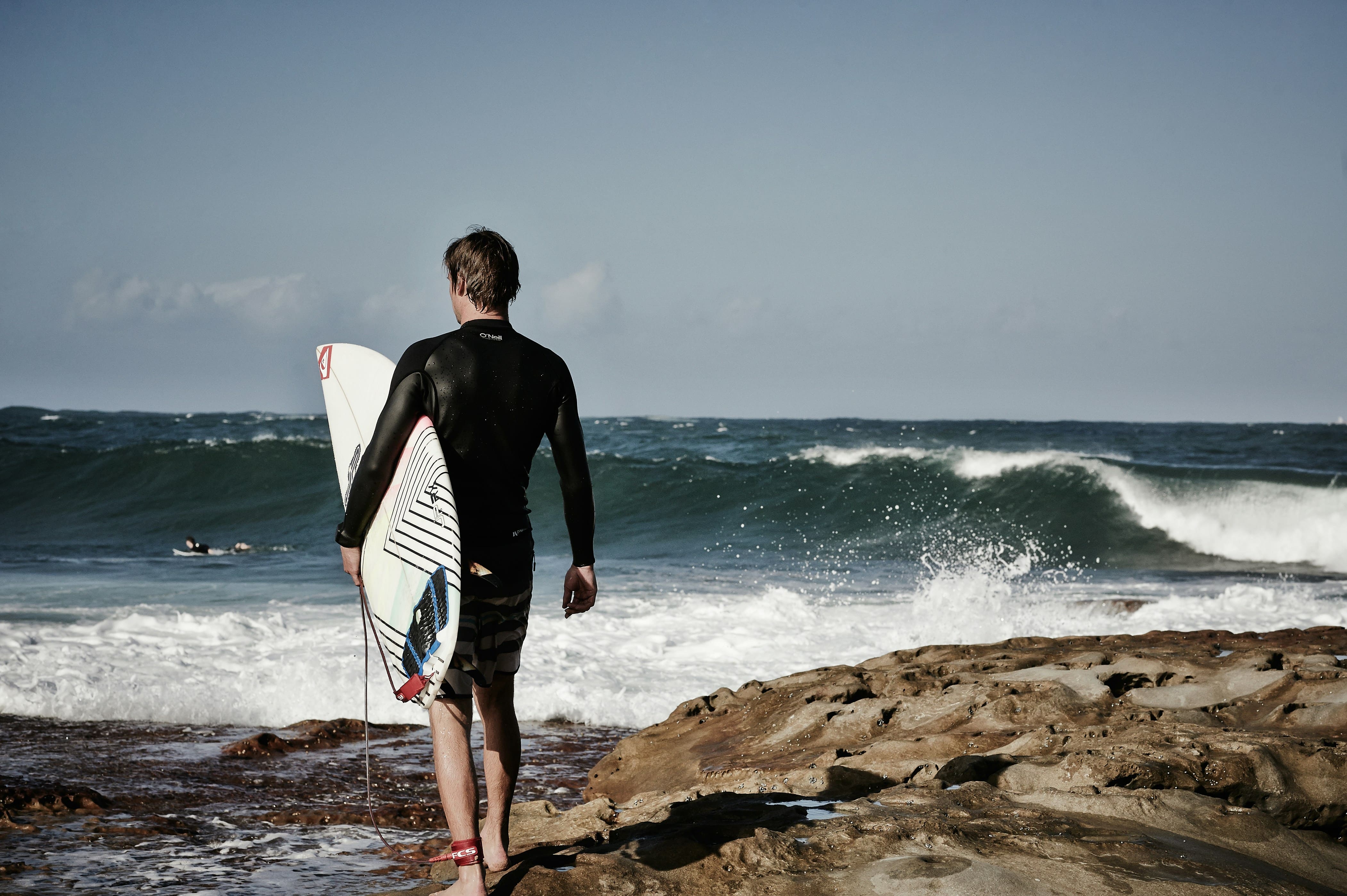 surfer standing in front of the ocean with a shortboard