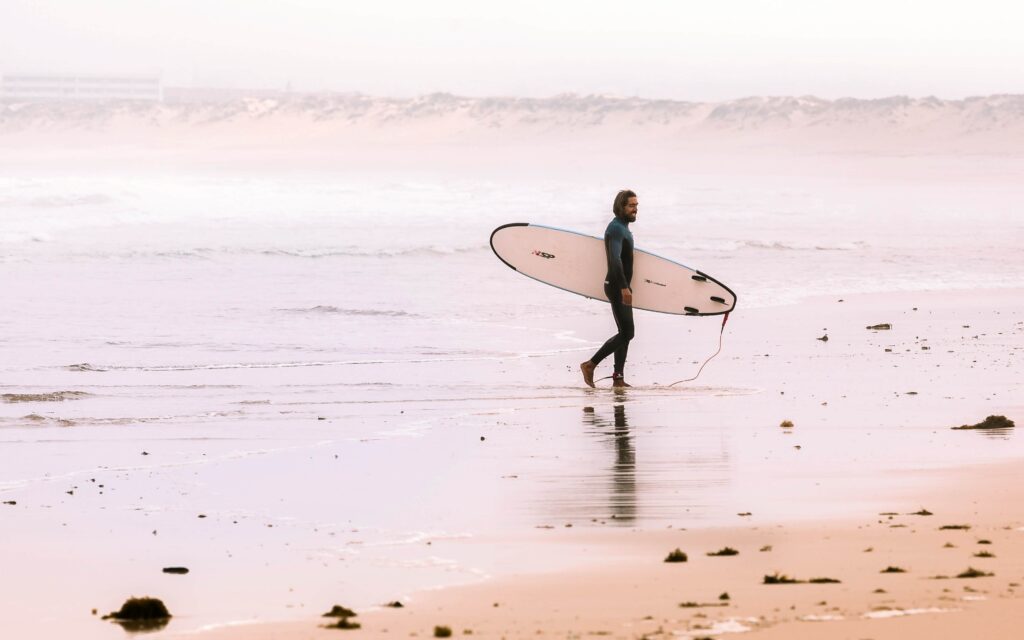surfer walking out of water with his surfboard
