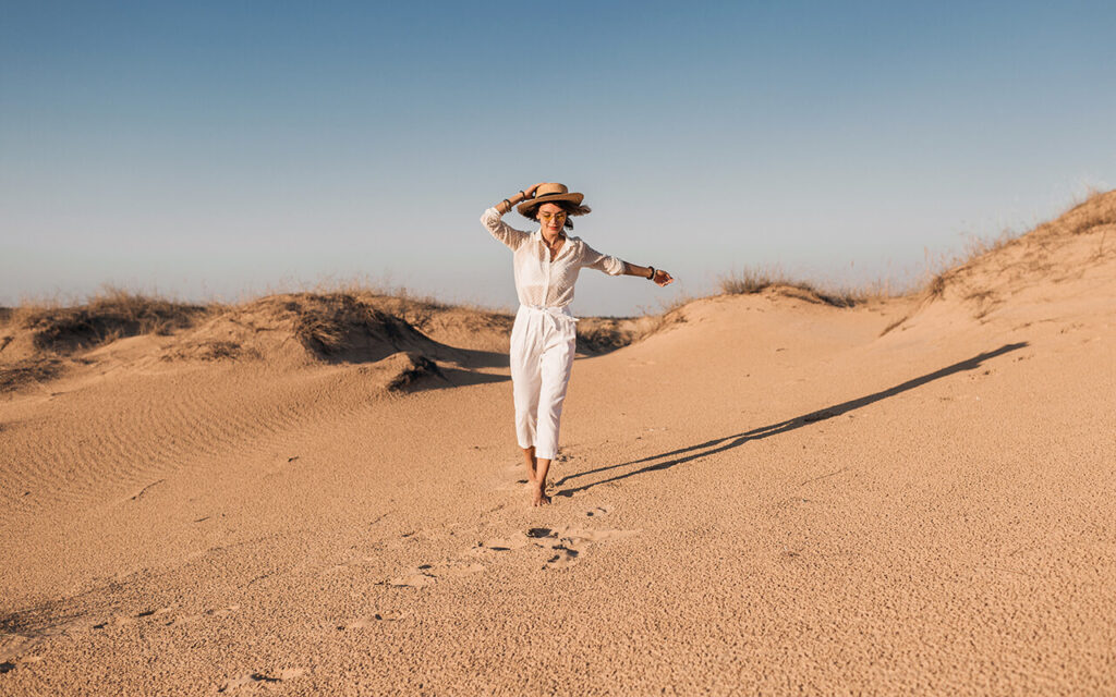 woman running in the desert with a straw hat