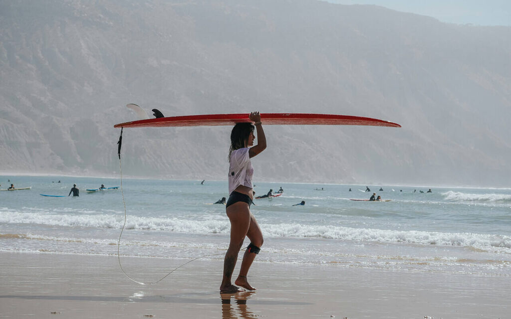 girl holding her surfboard on her head in imsouane bay during surf lessons morocco