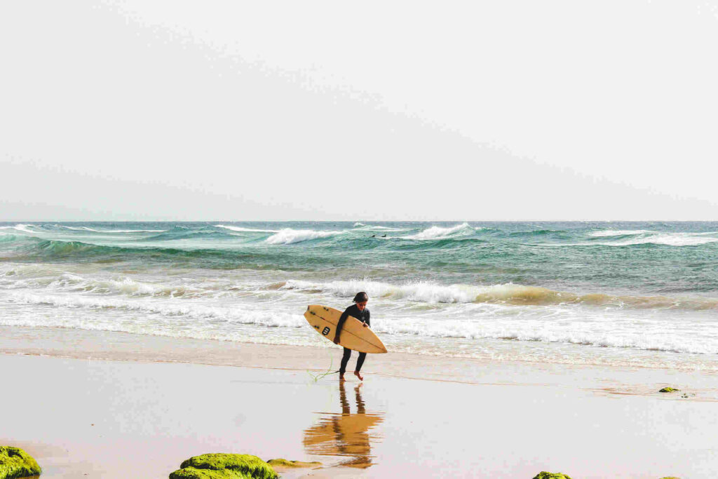 surfer with shortboard on an empty beach in agadir, morocco