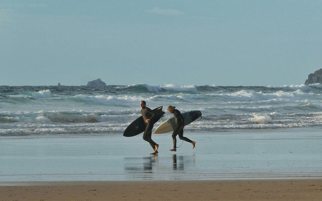 two surfers running on the sandy beach