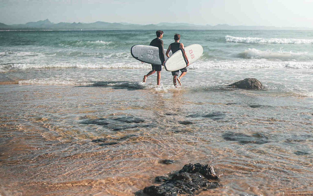 two surfers walking into the water with their shortboards