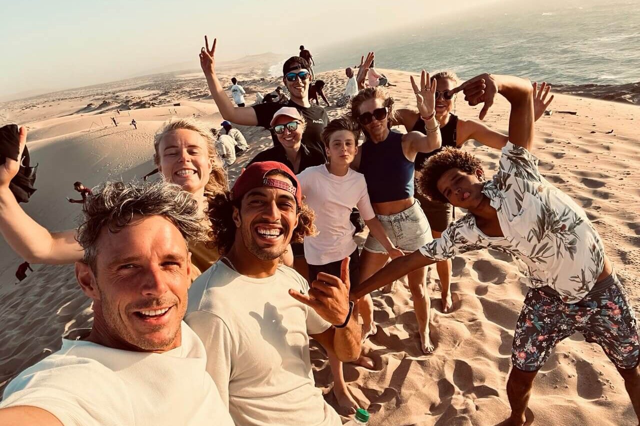a group of surfers in sand dunes of mini Sahara