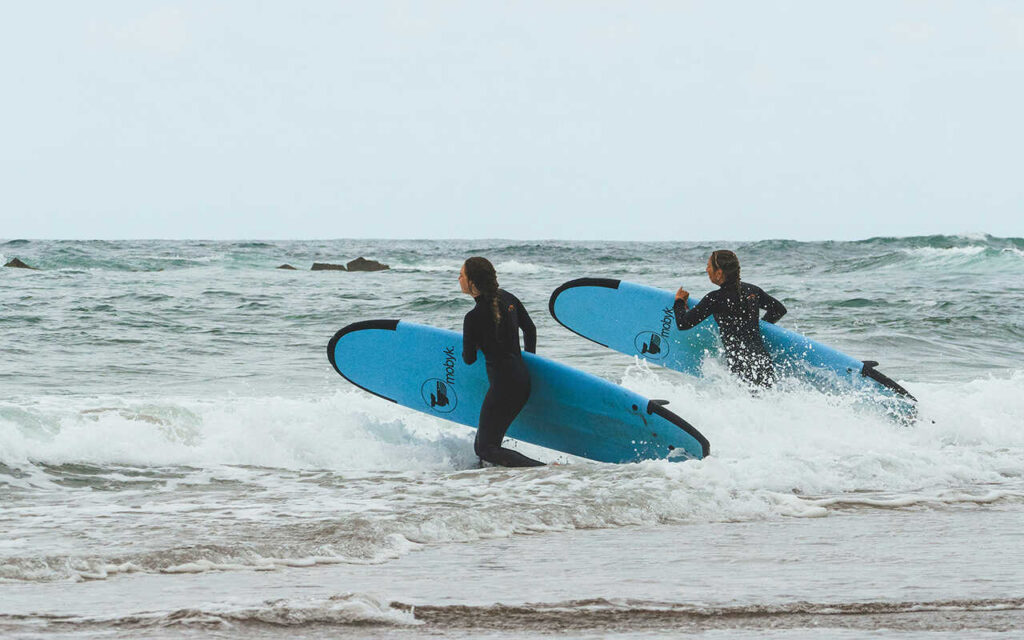 surfers going to the water with softtop blue surfboards
