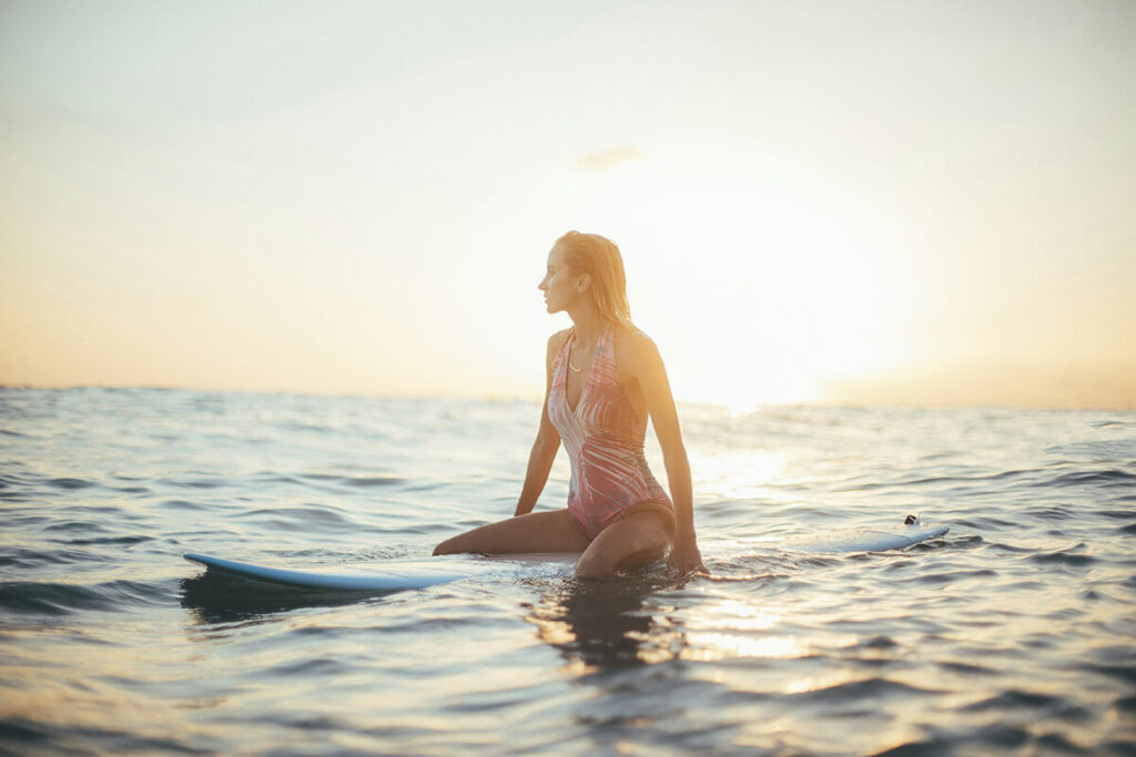 a surfer girl sitting on her surfboard in the lineup